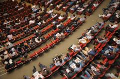 Seated delegates in rows of red chairs Seated delegates in rows of red chairs