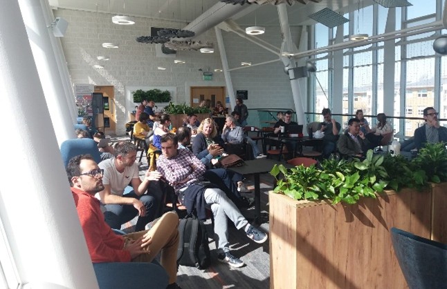 Image shows the audience to a Data Dialogues session hosted in the Sky Lounge of the Lancaster School of Computing. We can see about 22 people all engrossed in conversation about data.